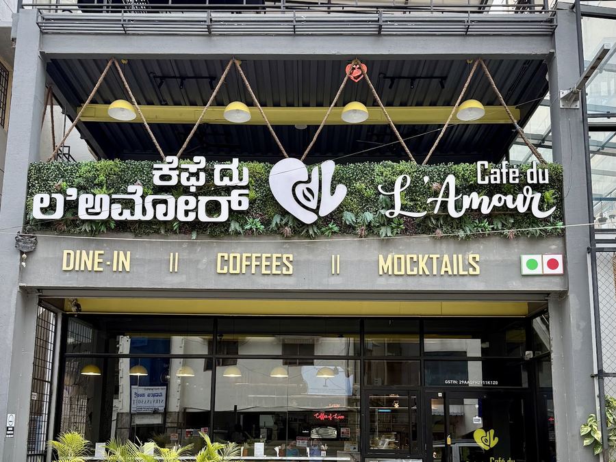 Café frontage with bilingual signage, the gold heart sculpture and a living green wall