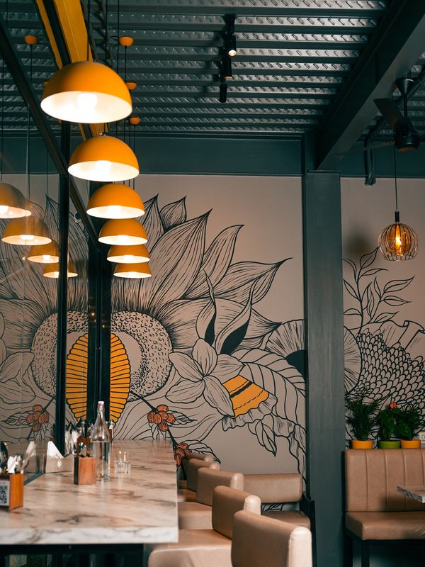 Close-up of the botanical wall mural under amber pendant lights, marble table in the foreground